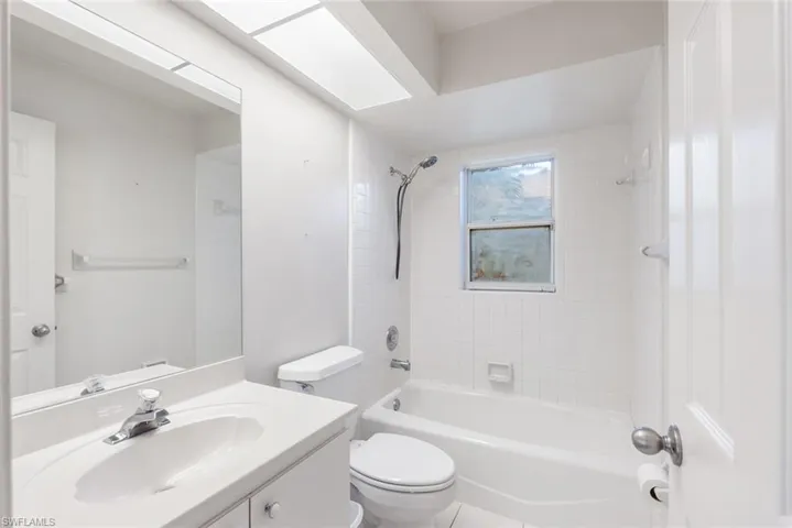 Full bathroom featuring tile flooring, tiled shower / bath, vanity, and toilet