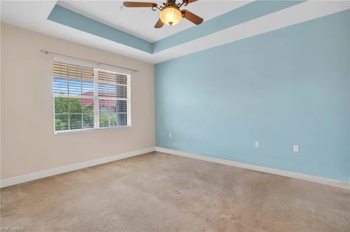 Carpeted spare room with ceiling fan and a tray ceiling