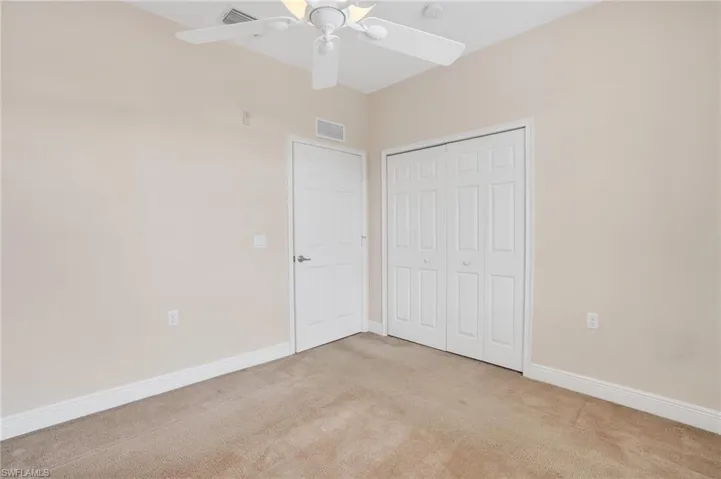 Unfurnished bedroom featuring light carpet, a closet, and ceiling fan