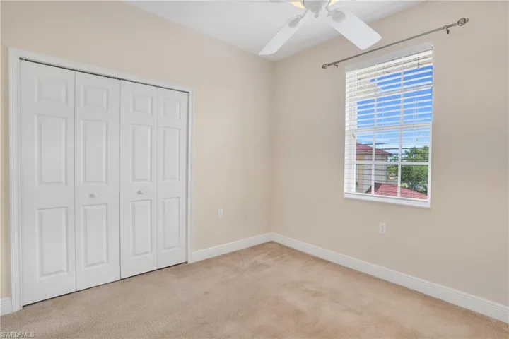Unfurnished bedroom featuring ceiling fan, a closet, and light carpet