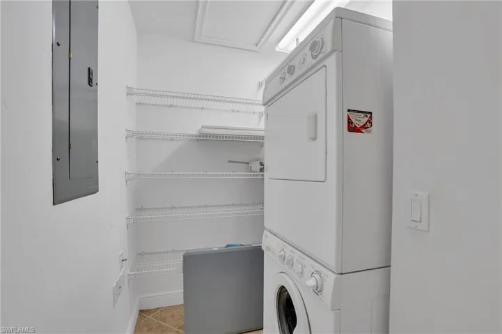 Laundry room featuring stacked washer and dryer and light tile floors