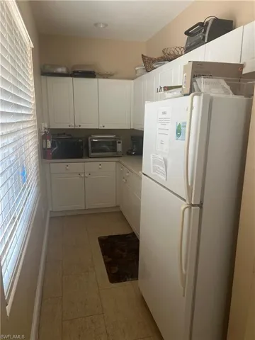 Kitchen with white cabinets, light tile flooring, and white refrigerator