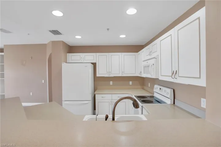 Kitchen with sink, white appliances, and white cabinetry