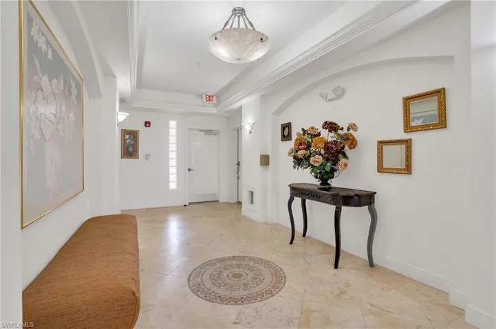 Tiled foyer entrance featuring ornamental molding and a raised ceiling
