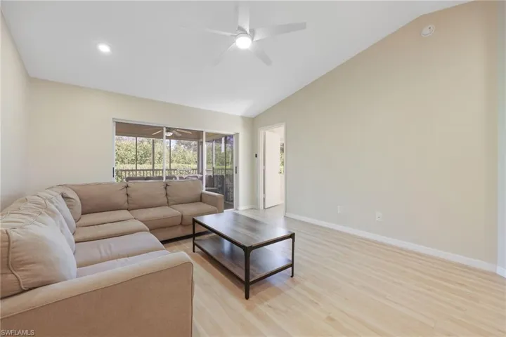 Living room featuring ceiling fan, light wood-type flooring, lofted ceiling, and a sunroom