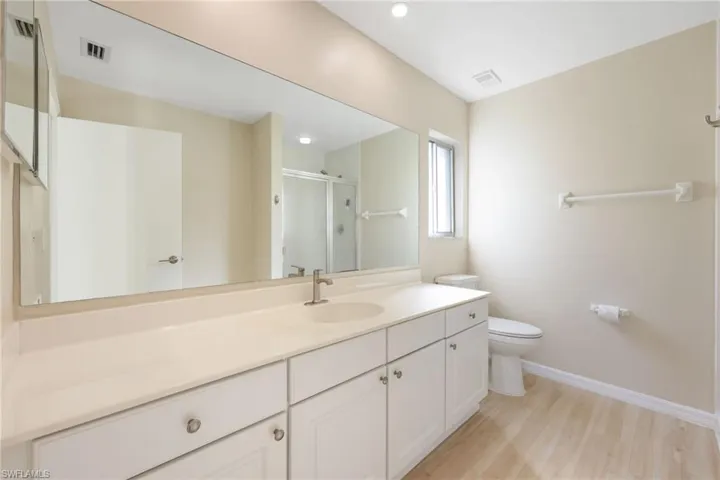 Bathroom featuring vanity, a stall shower, and light wood-style flooring