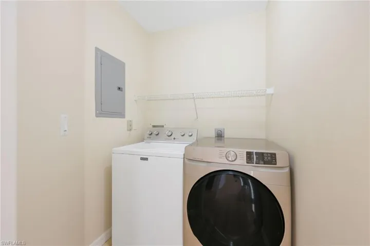 Laundry area featuring electric panel and washer and clothes dryer