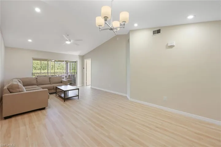 Living area featuring light wood-style floors, a ceiling fan, lofted ceiling, and suspended lighting