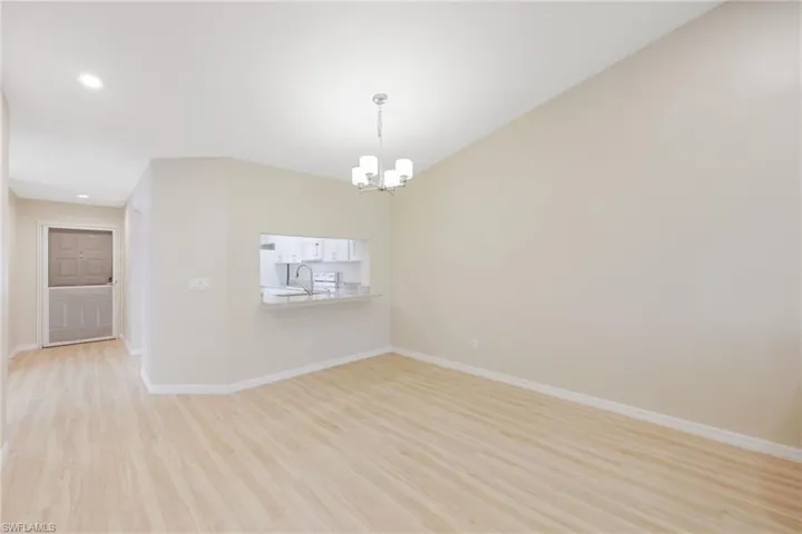 Empty room with light wood-type flooring and hanging lights
