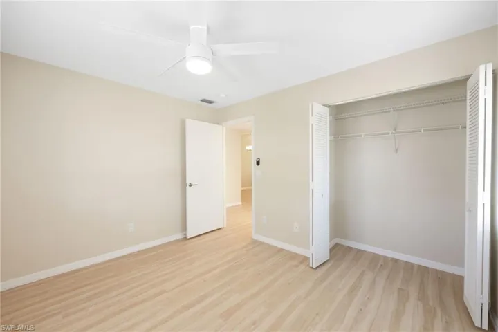 Unfurnished bedroom with light wood-style flooring, ceiling fan, and a closet