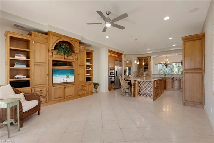 Tiled living room with ceiling fan with notable chandelier