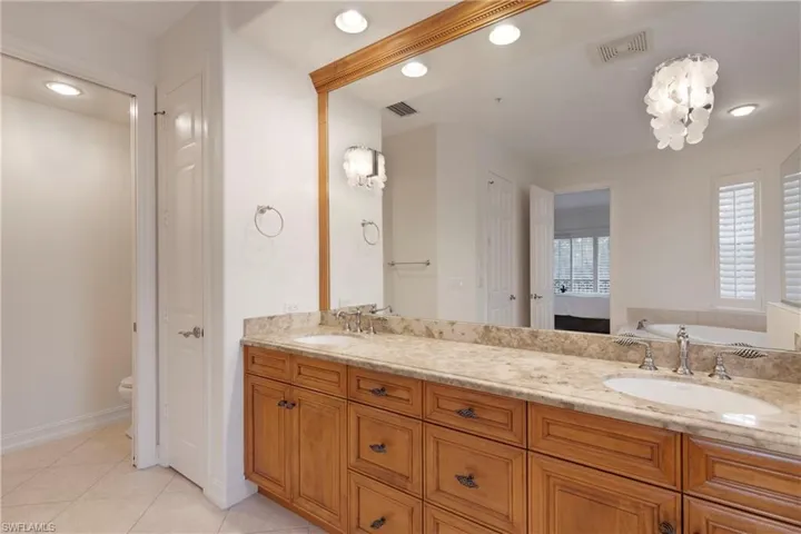 Bathroom featuring tile patterned flooring, vanity, toilet, and a bath