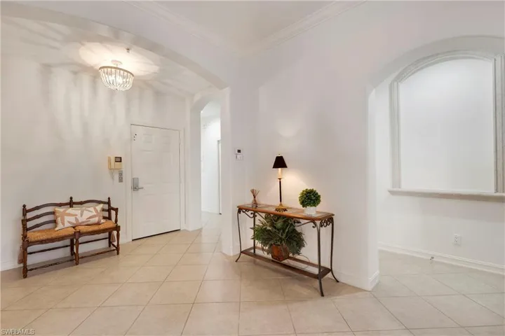Tiled entrance foyer with a chandelier and ornamental molding