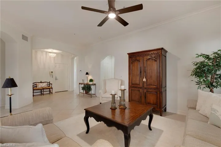 Tiled living room featuring crown molding and ceiling fan