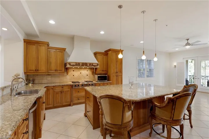 Kitchen with ceiling fan, sink, stainless steel appliances, pendant lighting, and custom range hood