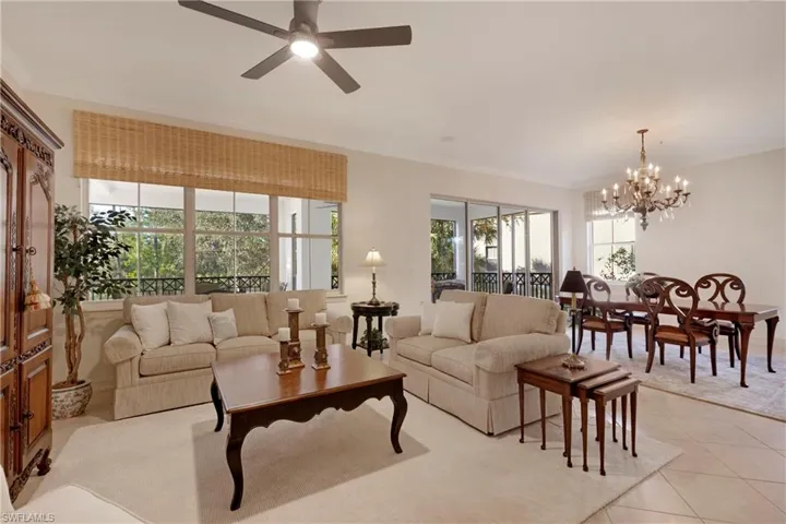 Tiled living room featuring ceiling fan with notable chandelier and ornamental molding