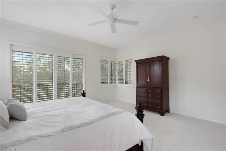 Carpeted bedroom featuring multiple windows, ceiling fan, and crown molding