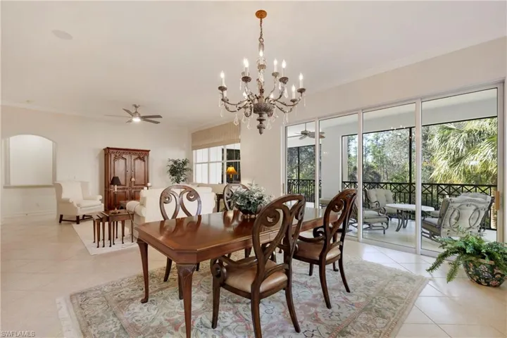 Dining room featuring ceiling fan with notable chandelier, light tile patterned floors, and ornamental molding