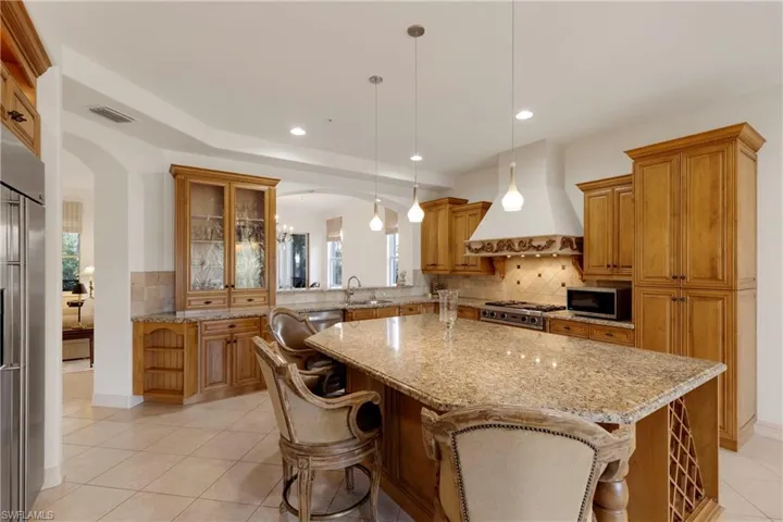 Kitchen featuring pendant lighting, custom exhaust hood, a center island, and appliances with stainless steel finishes