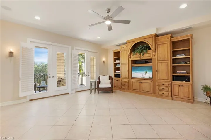 Living area featuring french doors, ceiling fan, built in shelves, and light tile patterned flooring