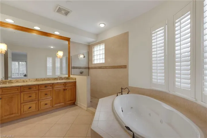 Bathroom featuring tile patterned flooring, shower with separate bathtub, vanity, and a chandelier