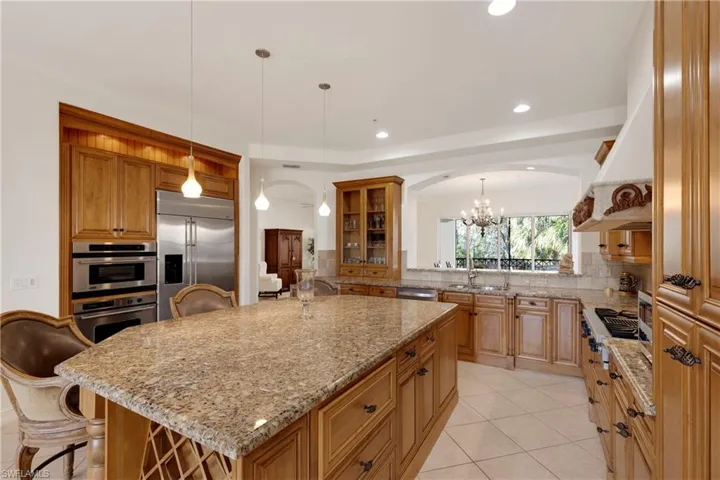 Kitchen featuring decorative light fixtures, a kitchen bar, stainless steel appliances, and an island with sink