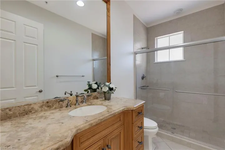 Bathroom with tile patterned floors, vanity, walk in shower, and toilet
