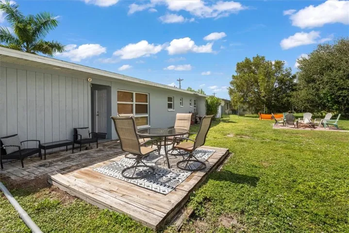 View of grassy yard with a patio, a fire pit, and a wooden deck