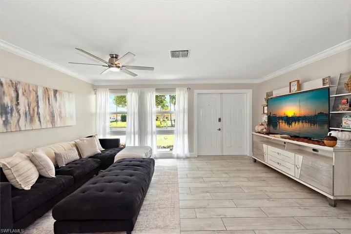 Living room with light wood finished floors, crown molding, and ceiling fan