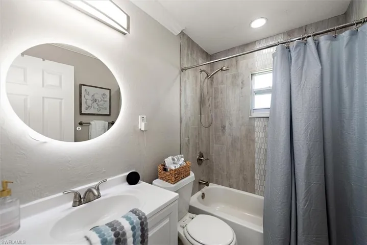 Full bathroom with shower / tub combo with curtain, vanity, and a textured wall