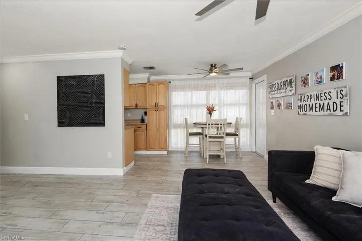 Living area featuring light wood-type flooring, crown molding, and ceiling fan