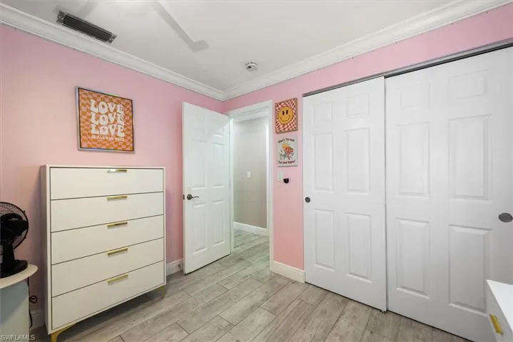 Bedroom featuring ornamental molding, light wood-style flooring, ceiling fan, and a closet