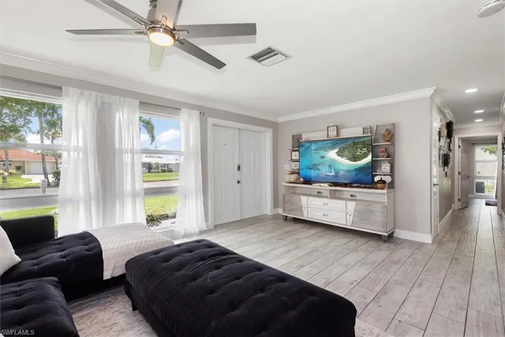 Living area with light wood-style flooring, ornamental molding, recessed lighting, and ceiling fan