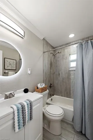 Full bath with shower / tub combo with curtain, vanity, and light wood-type flooring