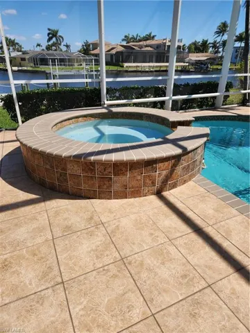 Outdoor pool featuring an in ground hot tub, a patio area, a residential view, and a lanai