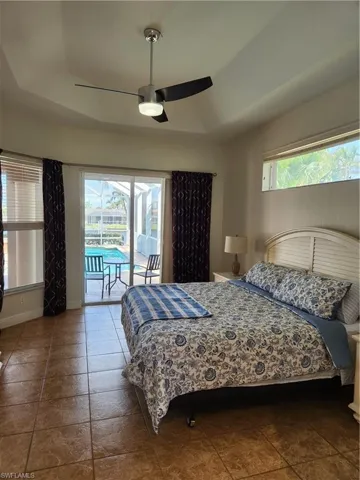 Bedroom with baseboards, lofted ceiling, ceiling fan, a raised ceiling, and access to outside
