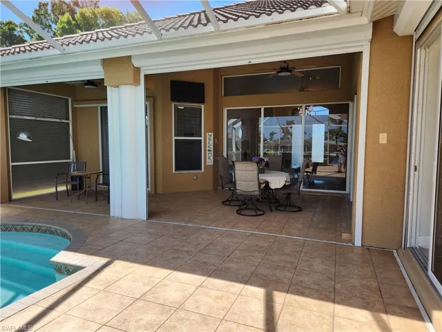 View of patio featuring an outdoor pool, a ceiling fan, a lanai, and outdoor dining space