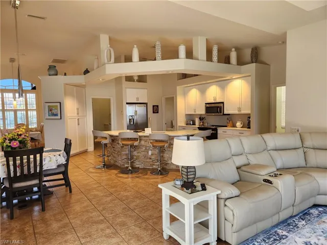 Living room with light tile patterned flooring, visible vents, and high vaulted ceiling