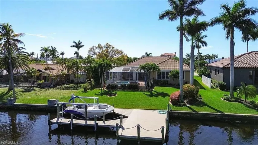 View of dock with glass enclosure, a water view, and a lawn