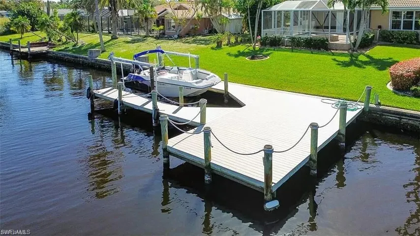 Dock area with a lawn, glass enclosure, and a water view