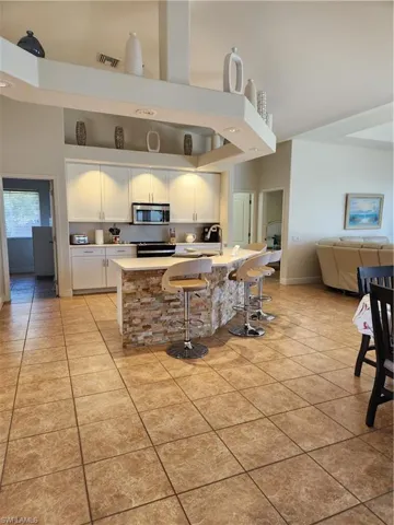 Kitchen with visible vents, a high ceiling, white cabinets, light countertops, and light tile patterned floors