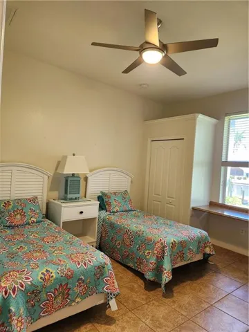 Bedroom with a closet, ceiling fan, and tile patterned flooring