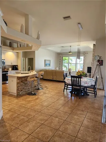 Kitchen with light tile patterned floors, a sink, light countertops, white cabinets, and open floor plan