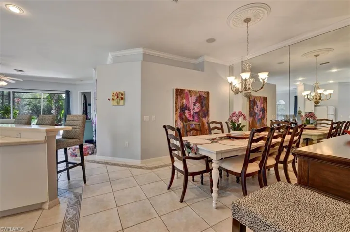 Dining area with ornamental molding, light tile floors, and ceiling fan with notable chandelier
