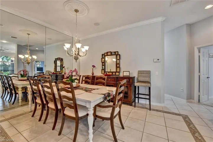 Dining area with light tile flooring, ceiling fan with notable chandelier, and crown molding