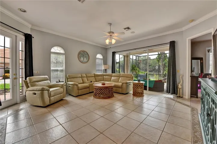 Tiled living room featuring ceiling fan and ornamental molding