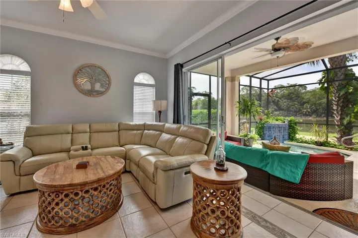 Living room with ceiling fan, crown molding, and light tile floors