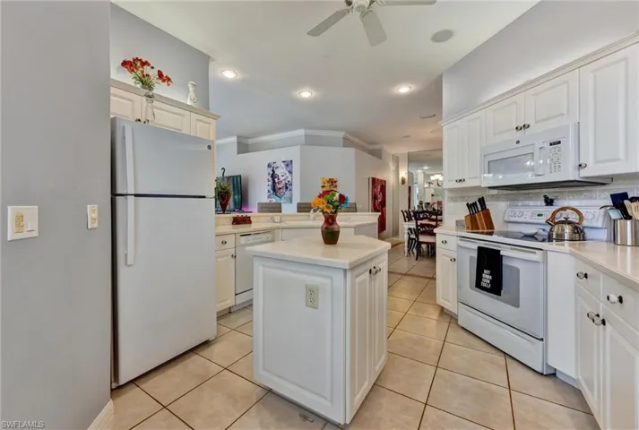 Kitchen with a kitchen island, ceiling fan, white appliances, and light tile floors