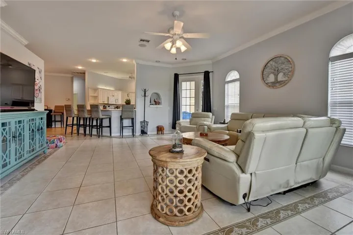 Living room with ceiling fan, crown molding, and light tile flooring