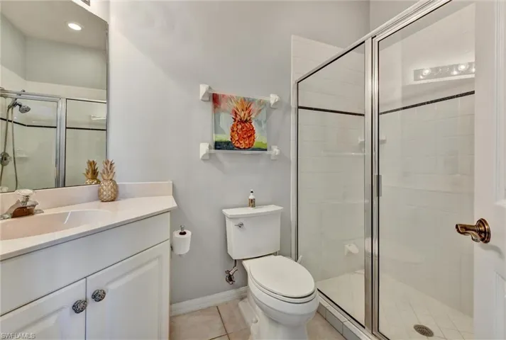 Bathroom with walk in shower, tile flooring, vanity with extensive cabinet space, and toilet